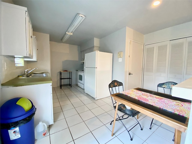 kitchen featuring sink, white appliances, light tile patterned floors, white cabinetry, and backsplash