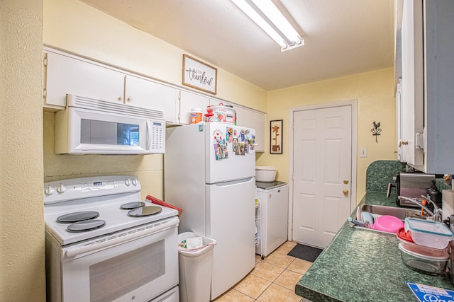 kitchen with white appliances, white cabinets, sink, light tile patterned flooring, and washer / dryer