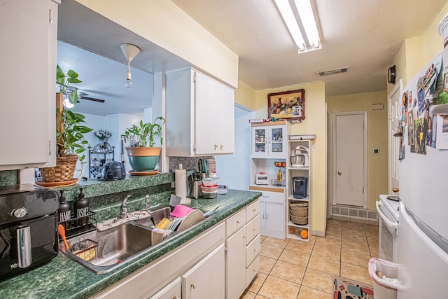 kitchen with white cabinetry, sink, light tile patterned flooring, and white appliances