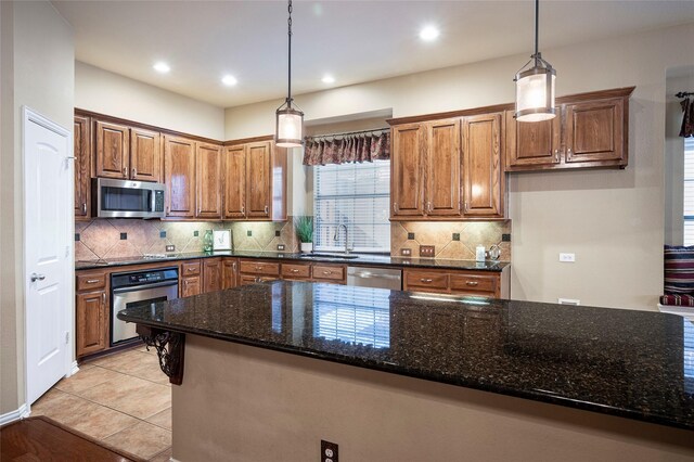 kitchen with decorative light fixtures, dark stone countertops, decorative backsplash, and appliances with stainless steel finishes