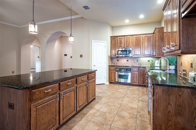 kitchen featuring a center island, crown molding, sink, light tile patterned floors, and stainless steel appliances