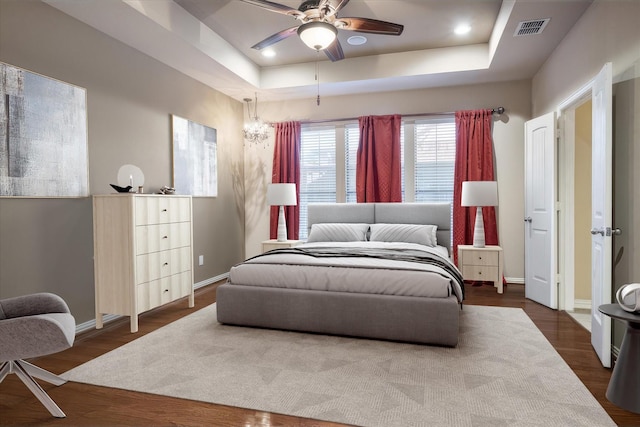 bedroom featuring a raised ceiling, ceiling fan, and dark hardwood / wood-style flooring