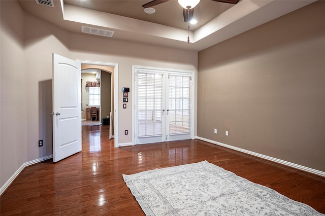 unfurnished room featuring ceiling fan, dark hardwood / wood-style flooring, and a tray ceiling