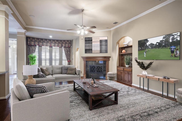 living room with hardwood / wood-style flooring, ceiling fan, ornamental molding, and a fireplace