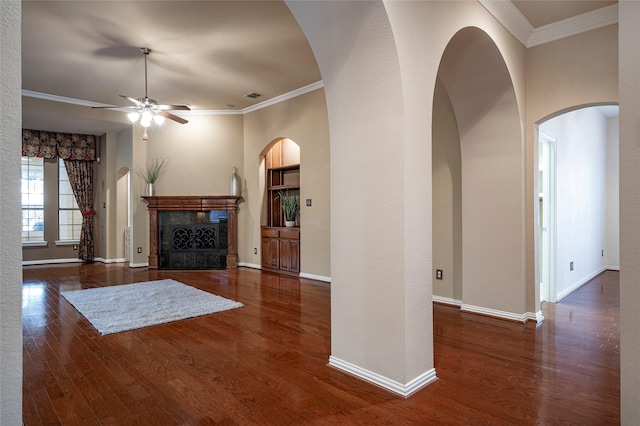 unfurnished living room with ceiling fan, crown molding, a premium fireplace, and dark wood-type flooring