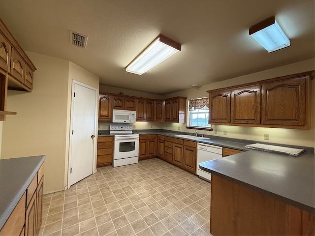 kitchen with a textured ceiling, white appliances, and sink