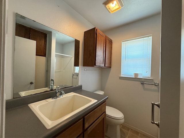 bathroom featuring tile patterned floors, vanity, toilet, and walk in shower