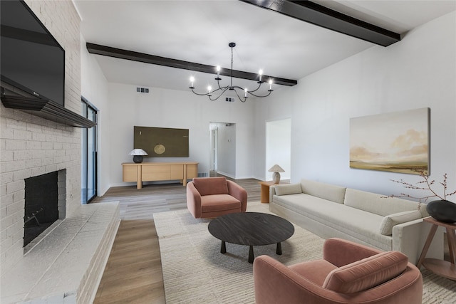 living room with a brick fireplace, beam ceiling, a notable chandelier, and light wood-type flooring