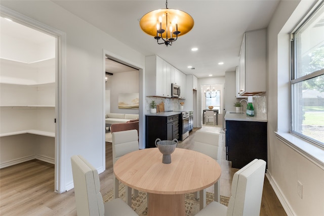 dining space with an inviting chandelier, sink, and light hardwood / wood-style floors