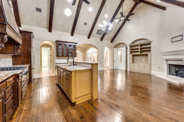 kitchen featuring dark hardwood / wood-style floors, high vaulted ceiling, sink, ceiling fan, and a center island with sink