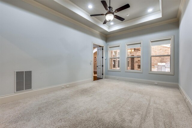 spare room featuring a tray ceiling, ornamental molding, and light colored carpet