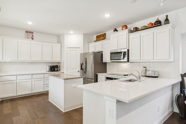 kitchen featuring white cabinetry, a center island, dark hardwood / wood-style flooring, backsplash, and appliances with stainless steel finishes