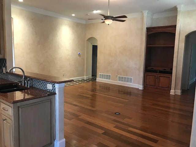 unfurnished living room featuring dark hardwood / wood-style floors, ceiling fan, crown molding, and sink