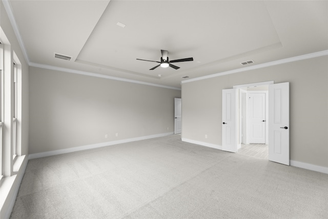 empty room featuring light colored carpet, ceiling fan, crown molding, and a tray ceiling