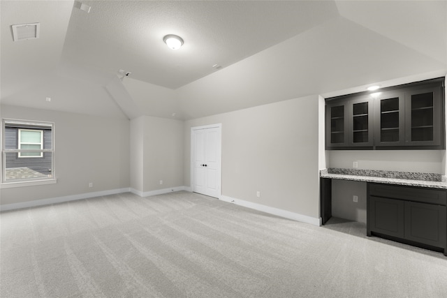 additional living space with light carpet and vaulted ceiling