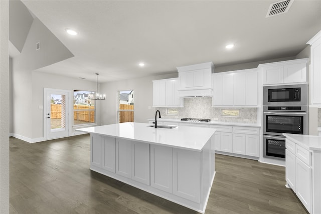 kitchen with appliances with stainless steel finishes, sink, white cabinetry, and an island with sink