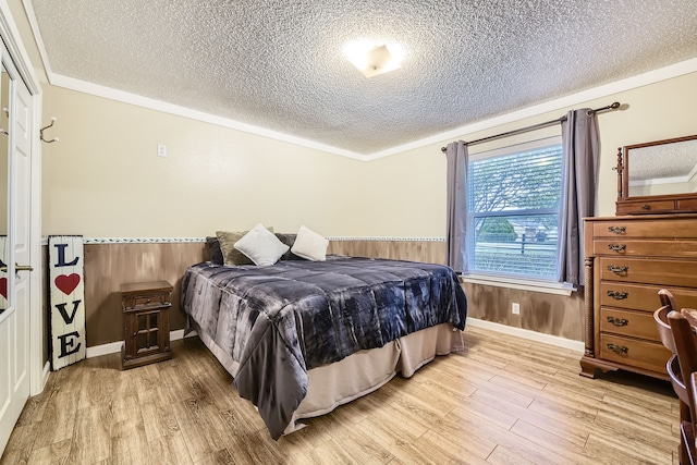 bedroom with wood walls, crown molding, light hardwood / wood-style floors, and a textured ceiling