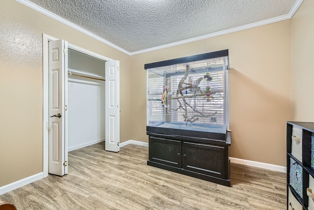 interior space with a closet, light hardwood / wood-style floors, a textured ceiling, and ornamental molding