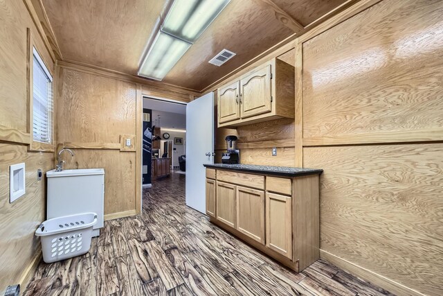 kitchen featuring light brown cabinets, dark hardwood / wood-style floors, wooden walls, and sink