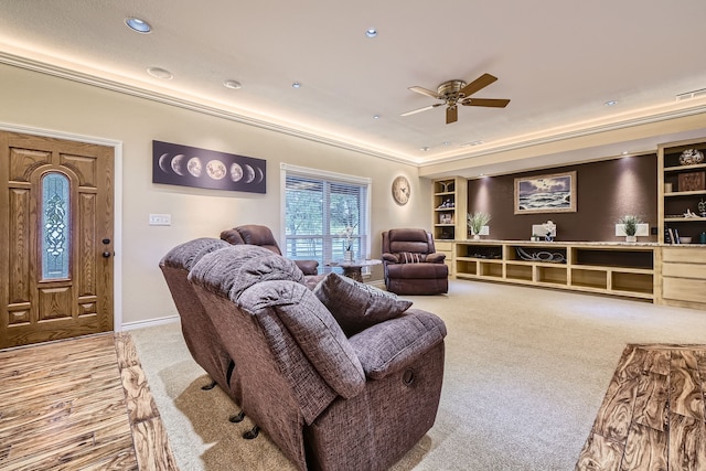 living room with ceiling fan, built in features, light colored carpet, and ornamental molding