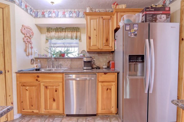 kitchen with appliances with stainless steel finishes, tasteful backsplash, and sink