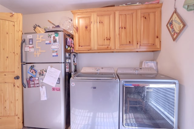 clothes washing area featuring washer and clothes dryer and cabinets