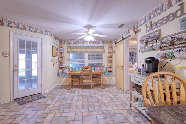 dining area featuring ceiling fan and a barn door