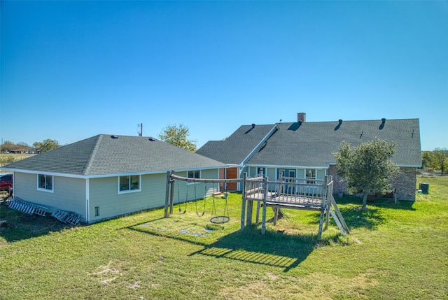 back of property featuring a playground, a deck, and a yard