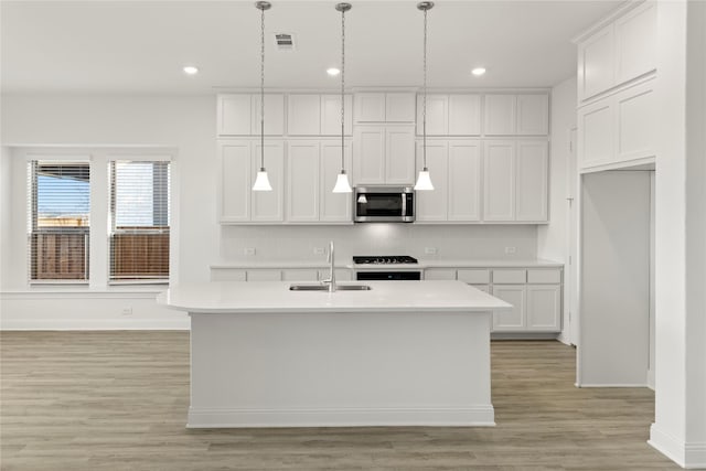 kitchen featuring white cabinetry, range, and an island with sink