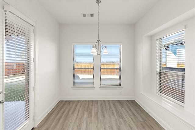 unfurnished dining area with a notable chandelier and light wood-type flooring