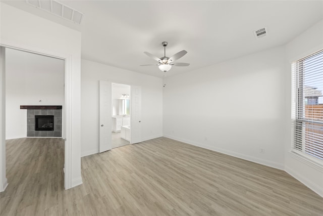 interior space featuring ensuite bath, a fireplace, ceiling fan, and light hardwood / wood-style flooring