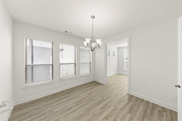 empty room with a chandelier and light wood-type flooring