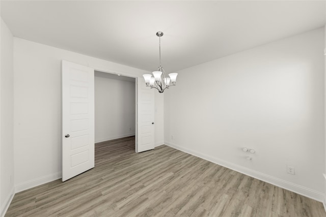 spare room with an inviting chandelier and light hardwood / wood-style flooring