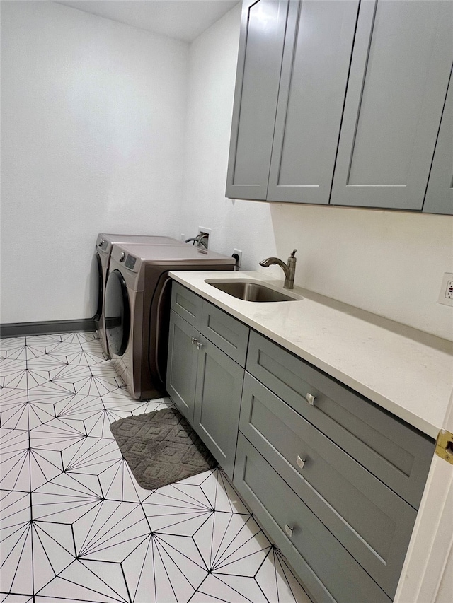 laundry area featuring washer and clothes dryer, sink, light tile patterned floors, and cabinets