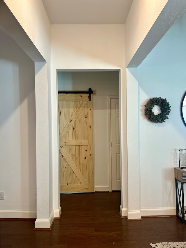 hallway with a barn door and dark wood-type flooring