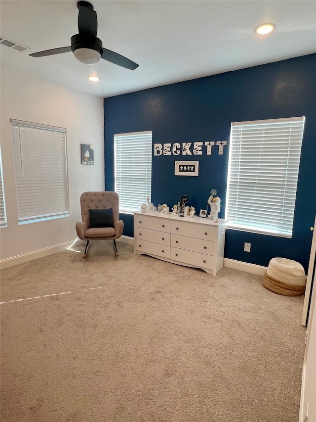 living area with carpet and ceiling fan