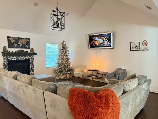 living room featuring dark hardwood / wood-style floors, a tile fireplace, and high vaulted ceiling