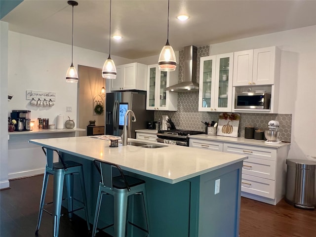 kitchen with a center island with sink, wall chimney exhaust hood, white cabinetry, and sink