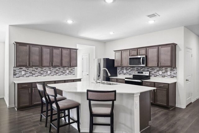 kitchen featuring dark hardwood / wood-style flooring, stainless steel appliances, and a center island with sink