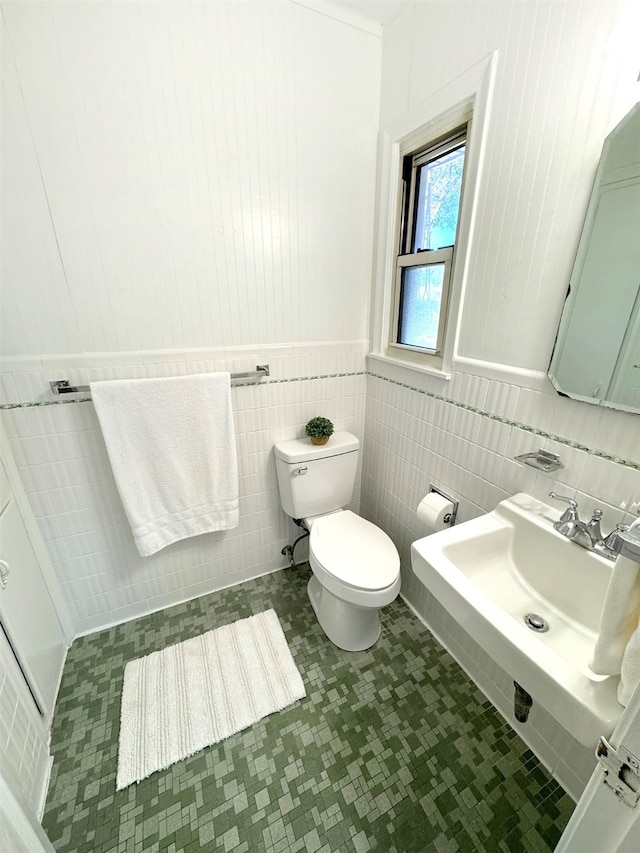 bathroom featuring tile patterned floors, toilet, and tile walls