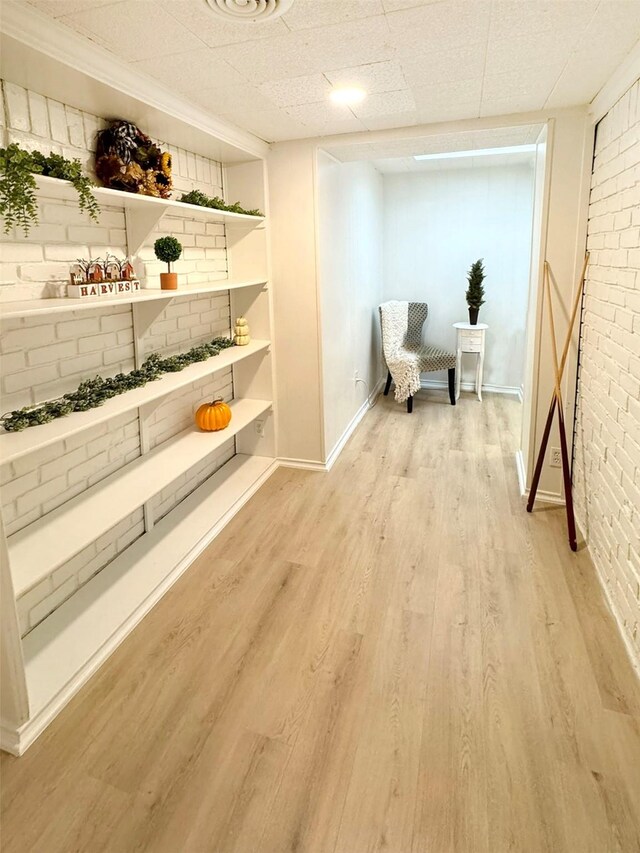 sitting room featuring light hardwood / wood-style floors, built in features, and brick wall