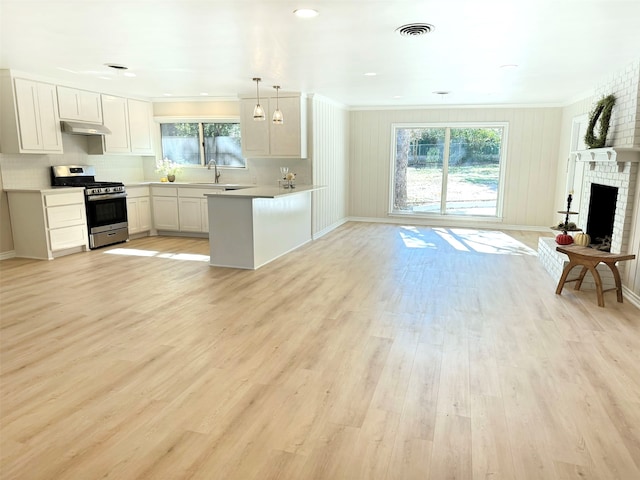 kitchen featuring kitchen peninsula, pendant lighting, white cabinetry, and stainless steel gas range