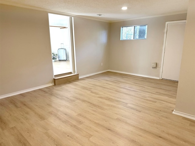 spare room with a textured ceiling, light wood-type flooring, and ornamental molding