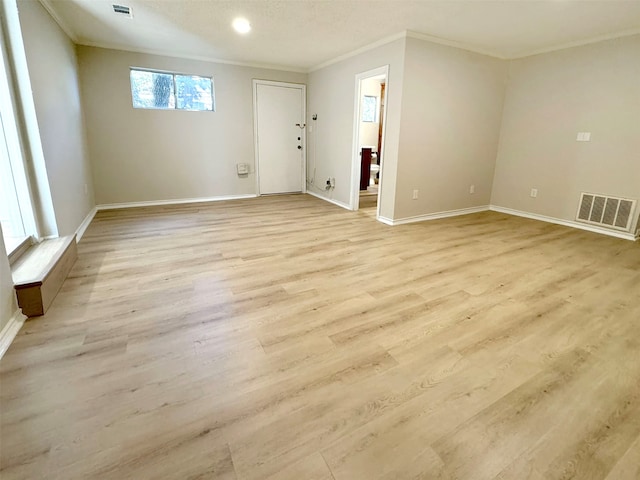 empty room with crown molding and light hardwood / wood-style flooring