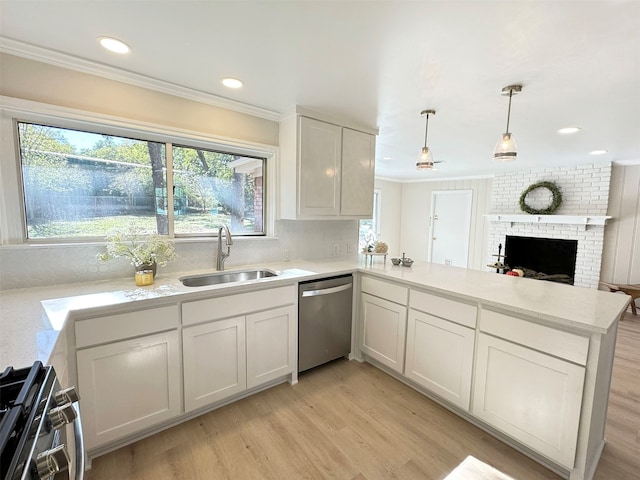 kitchen featuring sink, a brick fireplace, appliances with stainless steel finishes, light hardwood / wood-style floors, and kitchen peninsula