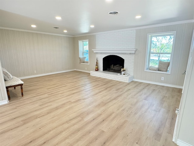 unfurnished living room featuring a fireplace, a wealth of natural light, light hardwood / wood-style flooring, and ornamental molding