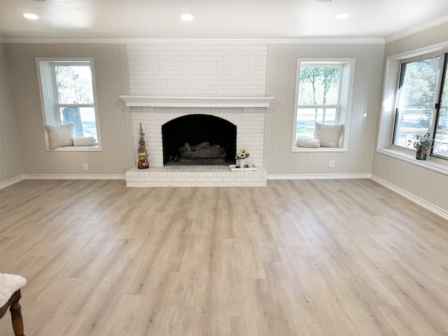 unfurnished living room featuring plenty of natural light, crown molding, a fireplace, and light hardwood / wood-style flooring