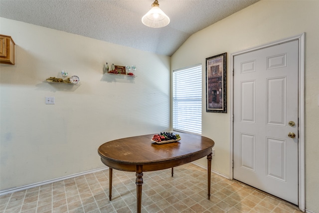 dining space featuring a textured ceiling and lofted ceiling