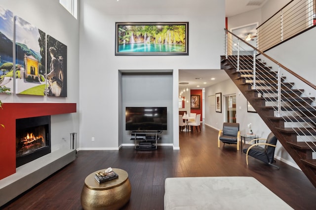 living room featuring dark hardwood / wood-style flooring and a towering ceiling