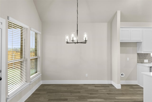 unfurnished dining area with a chandelier, dark hardwood / wood-style floors, and vaulted ceiling